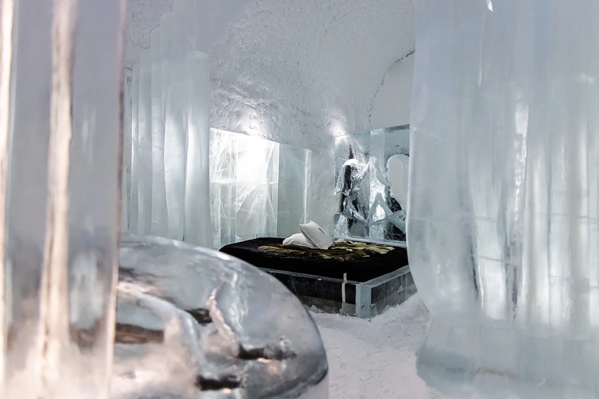 A carved ice wall lit from behind in a snow vault.
